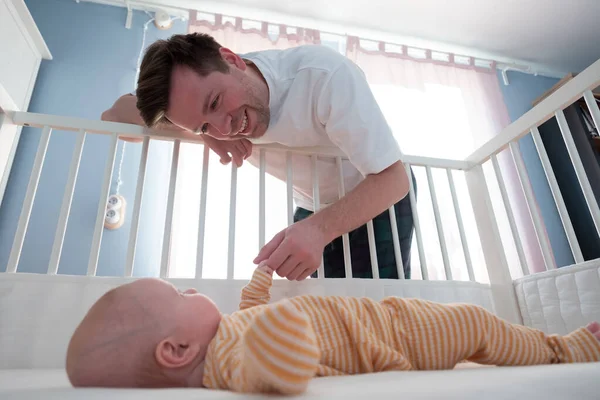 Young man playing with his little baby in bed — Stock Photo, Image