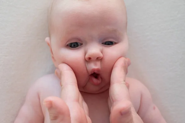 Pais beliscar bochechas um bebê recém-nascido menina fazendo cara de peixe — Fotografia de Stock