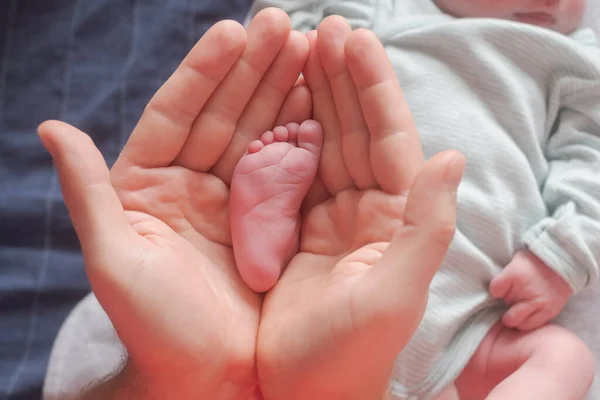 Ouder houden kleine voet van zijn pasgeboren baby. — Stockfoto