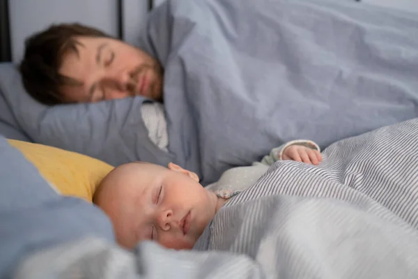 Schlafender Vater und niedliches Kind liegen zusammen im Bett. — Stockfoto