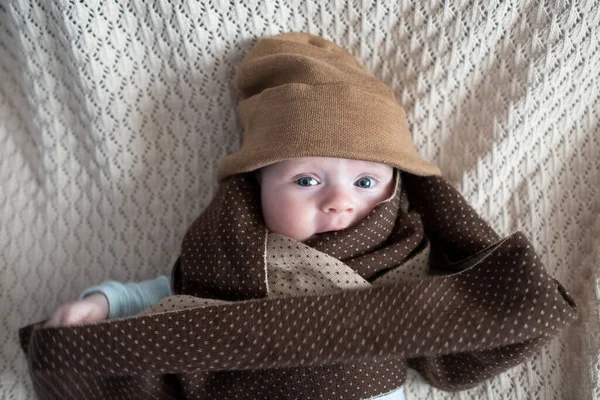Lindo bebé con grandes ojos azules con un sombrero y una bufanda de punto enorme — Foto de Stock