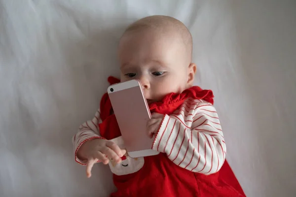 Baby spielt mit Handy und hält es zum ersten Mal in ihrem Leben in der Hand. — Stockfoto