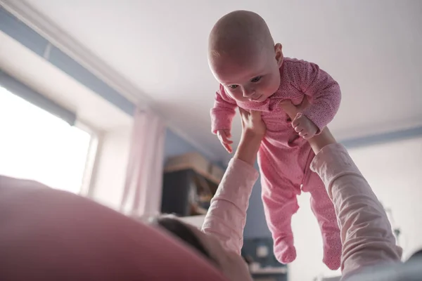 Portrait of caucasian mother lifting and playing with newborn baby, baby talking to mother. — Stock Photo, Image