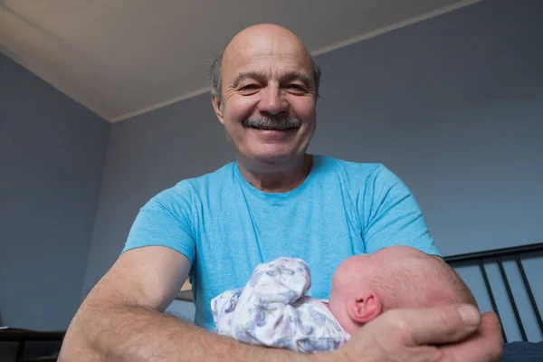 Grandfather holding a caucasian newborn baby girl — стоковое фото
