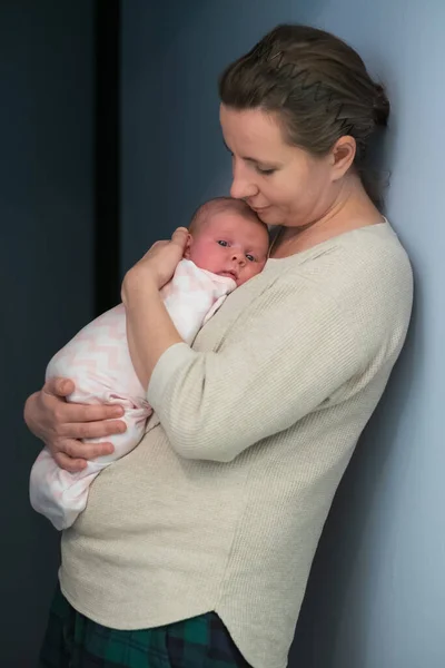 Zorgzame jonge moeder leunen op de borst pasgeborene. Geniet thuis van een teder familiemoment — Stockfoto