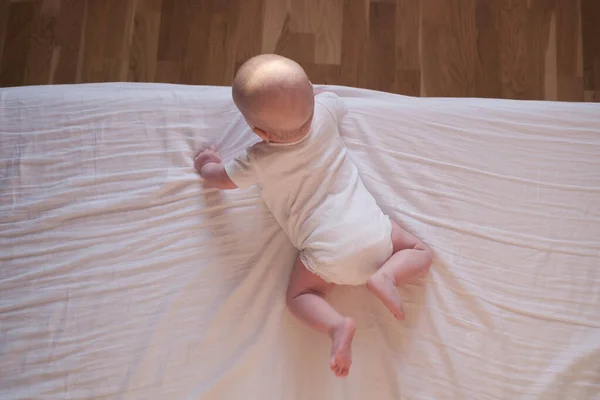 Caucásico bebé arrastrándose hasta el borde de la cama. — Foto de Stock