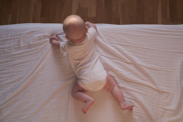 Caucásico bebé arrastrándose hasta el borde de la cama. — Foto de Stock