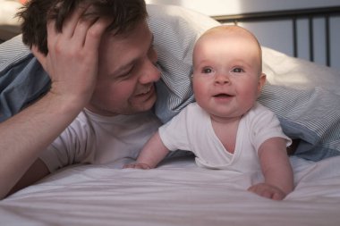 Caucasian father and cute child resting together in bed.