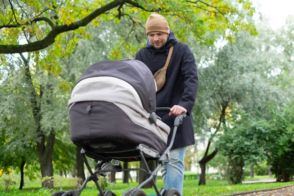 Jovem pai feliz com carrinho de bebé durante o passeio na natureza — Fotografia de Stock
