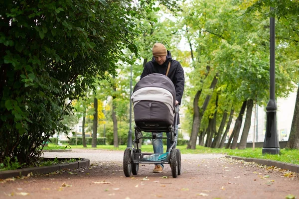 Szczęśliwy młody ojciec z wózka podczas spaceru w przyrodzie — Zdjęcie stockowe