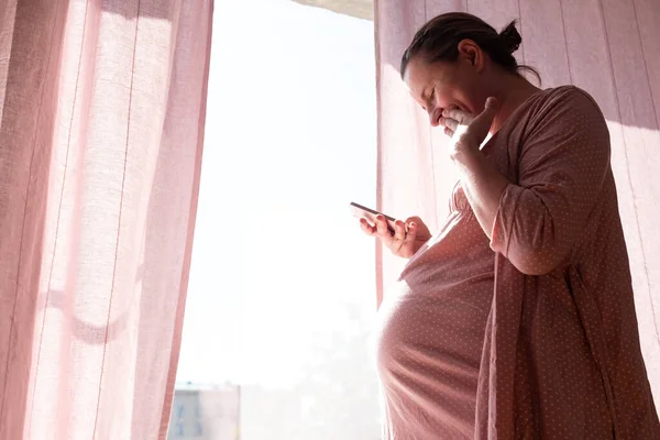 Happy pregnant caucasian woman reading sms smiling — Stock Photo, Image
