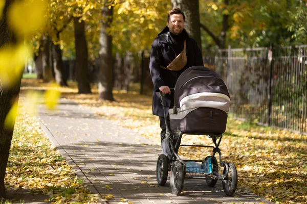 Gelukkig jonge vader met pram tijdens de wandeling in de natuur — Stockfoto