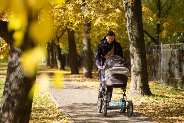 Счастливый молодой отец с коляской во время прогулки на природе — стоковое фото