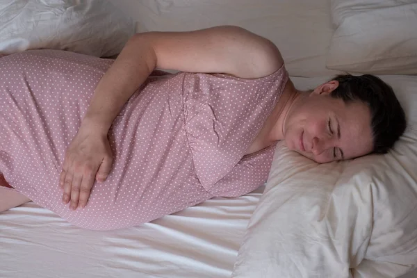 Mujer embarazada durmiendo tranquilamente en el dormitorio — Foto de Stock
