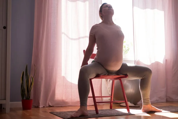 Mujer embarazada en la alfombra de fitness, entrenamiento en casa — Foto de Stock