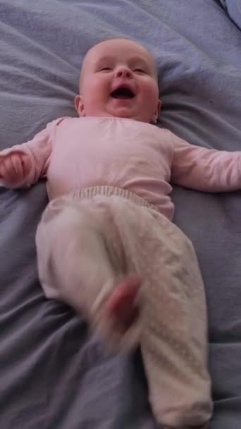 Кавказский ребенок лежит на кровати и смеется.. — стоковое видео