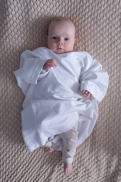 Caucasian baby dressed in father t-shirt lying on the bed — Stock Photo, Image