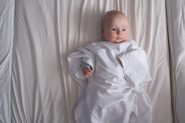 Caucasian baby dressed in father t-shirt lying on the bed — Stock Photo, Image