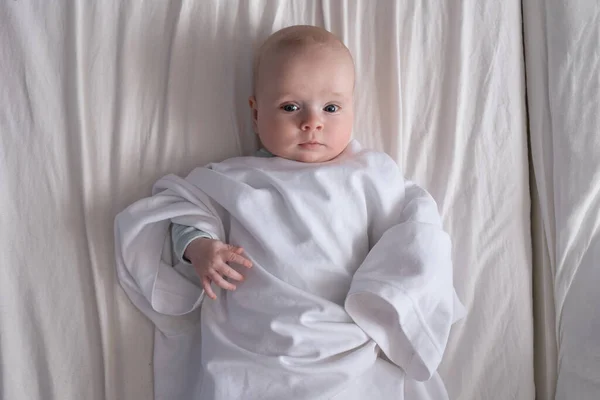 Bebé caucásico vestido con camiseta de padre acostado en la cama — Foto de Stock