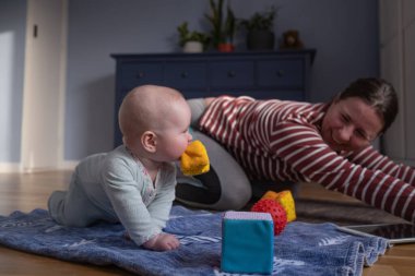 Bebekli anne güçlü ve sağlıklı olmak için evde yoga yapıyor.