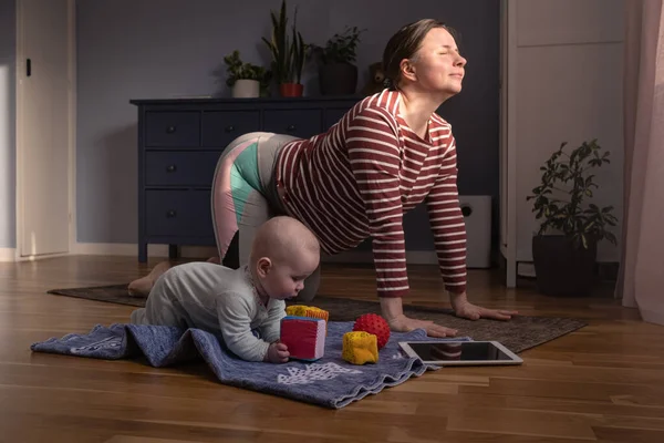 Bebekli anne güçlü ve sağlıklı olmak için evde yoga yapıyor. — Stok fotoğraf