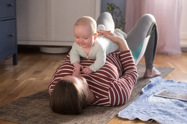 Bebekli anne güçlü ve sağlıklı olmak için evde yoga yapıyor. — Stok fotoğraf