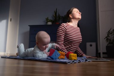 Beyaz anne ve bebek güçlü ve sağlıklı olmak için evde yoga yapıyorlar.,