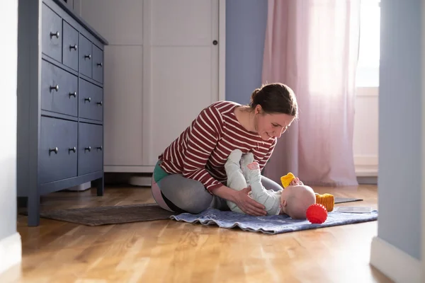 Λευκή μητέρα με μωρό κάνει γιόγκα στο σπίτι για να είναι ισχυρή και υγιής, — Φωτογραφία Αρχείου