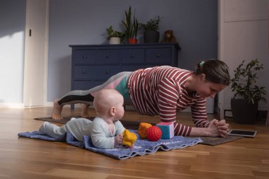 Beyaz anne ve bebek güçlü ve sağlıklı olmak için evde yoga yapıyorlar.,