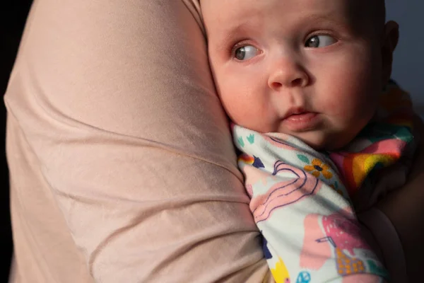 Bayi melihat ke samping duduk di tangan ibunya — Stok Foto