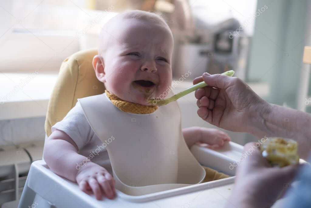 Adorable little toddler child or infant baby crying, do not want eating food on baby chair