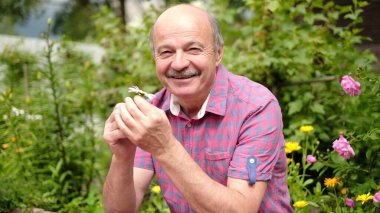 Son sınıf öğrencisi beyaz papatya çiçeğini kokluyor. Yaz tatili boyunca bahçeye çıkıp güneşli günün tadını çıkarıyor.