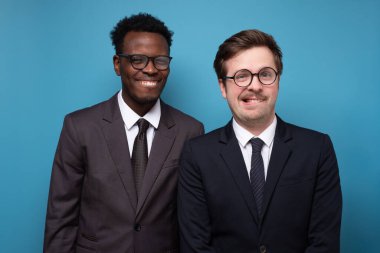 Komik suratlı, takım elbiseli iki genç adam kameraya bakıyor..