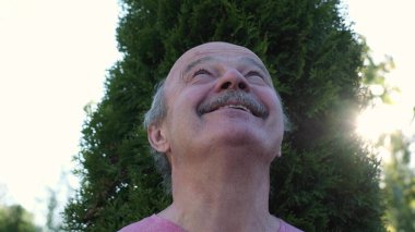 Bir yaz parkındaki mutlu yaşlı adam etrafa bakınıyor..