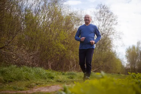 Aktif kıdemli adam parkta koşuyor. Sağlıklı emeklilik yaşam tarzı.