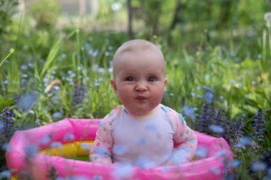 Bebek sıcak bir yaz gününde bahçede köpük banyosunda oturuyor. Açık hava su tedavileri.