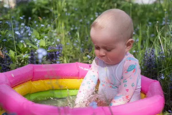 Bebek sıcak bir yaz gününde bahçede köpük banyosunda oturuyor. Açık hava su tedavileri.
