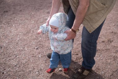 Küçük kız bir adamla dışarı çıkıyor. Büyükbaba torununun yürümesine yardım ediyor.