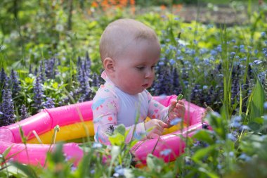 Bebek sıcak bir yaz gününde bahçede köpük banyosunda oturuyor. Açık hava su tedavileri.