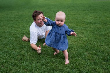 Mutlu çocuk küçük kız ders çalışıyor yeşil çimlerde oyuncakları elinde tutarak.