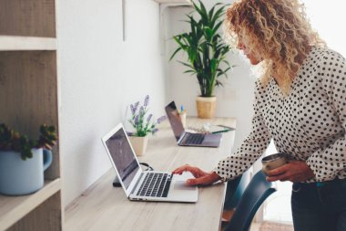 Bildirimleri kontrol etmek ya da mesaj göndermek için dizüstü bilgisayar kullanan ev işyeri masaüstü ve iş kadını