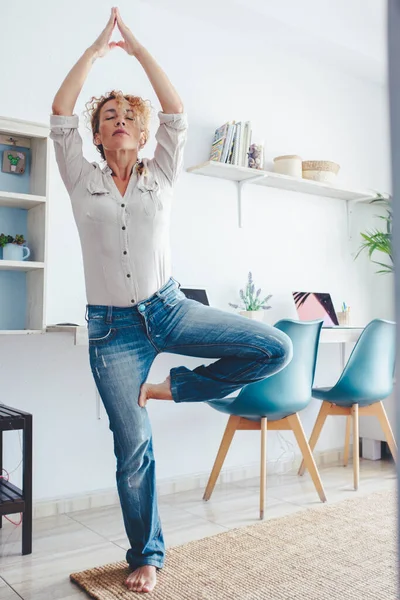 家庭保健和瑜伽锻炼活动 穿着休闲装的成年妇女在客厅里做着平衡的姿势 — 图库照片