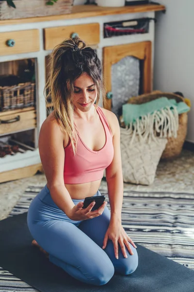 Spor Salonundaki Kadın Yoga Minderinde Diz Çöküyor Cep Telefonu Kullanıyor — Stok fotoğraf