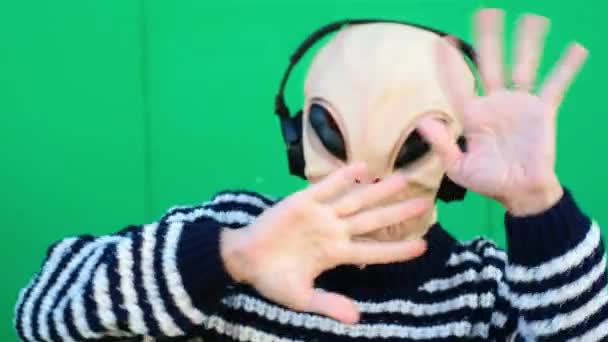 Person Alien Mask Headphones Posing Green Wall Pointing Fingers — Video Stock