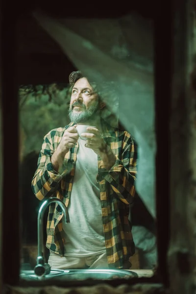 Mature Adult Man Home Viewed Thrugh Glass Winws Drinking Coffee — Stockfoto