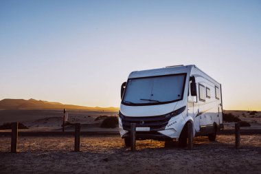Big motorhome camper parked off road with desert and blue sky in background. Travel lifestyle camping car and freedom. Van against sunlight parked off road. Concept of wanderlust vanlife travelers lifestyle