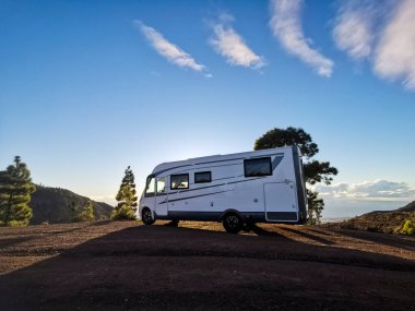 Gün batımı ışıklarına ve ağaçlara parkedilmiş bir karavan. Alternatif yaşam tarzı vanlife ve seyahat tutkusu kavramı. Kamp arabasıyla yaz tatili.