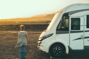 Alternatif turist karavanı konsepti. Büyük bir karavanın yanında duran kadın özgürlüğün ve çöl manzaralı doğanın tadını çıkarıyor. Seyahat eden insanların yaşam tarzları