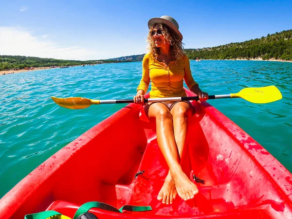青い水の湖を旅する赤いカヤックに座っている女性を楽しんだ 夏休み旅行の経験で活発な観光客の女性の広い角度ビュー — ストック写真