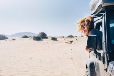 Gezgin kadın mutlu bir gülümseme ve açık havada park etmiş siyah arabasının dışında eğleniyor. Yaz tatili macerası. Tüm arazi aracıyla çölde alternatif bir turist. İnsan yaşam tarzı